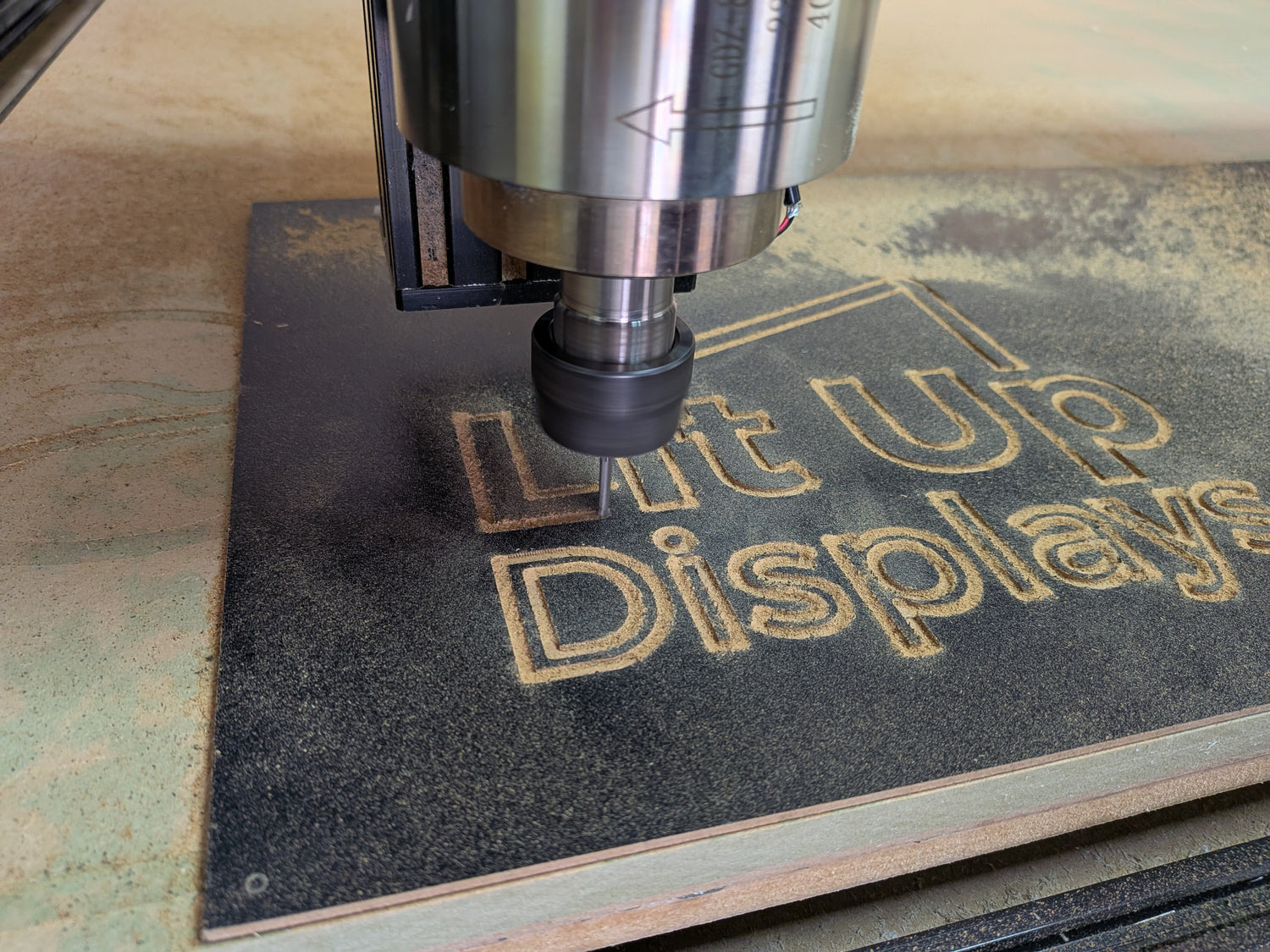 CNC machine engraving text on a wooden surface in workshop